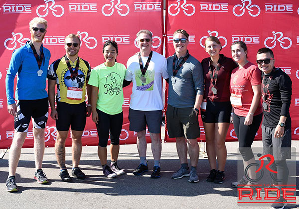 Eight members of the 2018 Medical Physics team in front of a red The Ride background